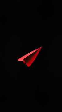 A red paper plane is flying through a dark background. The scene captures the concept of movement and creativity. It focuses on the shape and color
