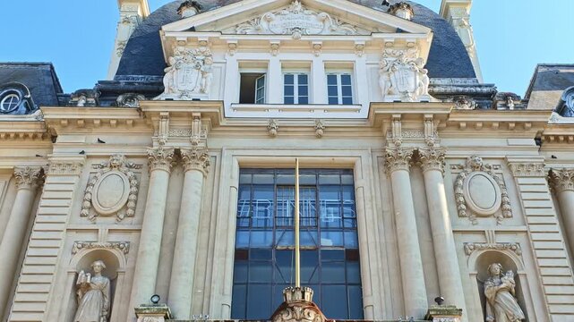 Ornate Palais du Commerce facade in Rennes, featuring a monumental pediment, Corinthian columns, sculpted figures, decorative medallions, balustrades and mansard slate roofing, France, pan down reveal