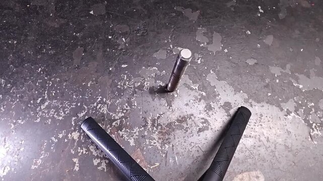 Angle grinder sits close to damaged metal as maintenance repair begins. Yellow handheld tool points toward bolt and rough steel, with scratched surface indicating heavy use and surface cleanup.