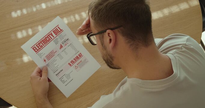 Man shocked by an extremely high electricity bill, struggling with rising energy prices and expensive household costs.