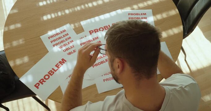 Overwhelmed man surrounded by multiple problem signs, expressing frustration, stress and difficulty dealing with many problems at once.