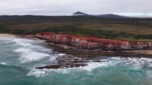 Aerial video flying over the rugged coastline at Lake Arragan, featuring sandy shoreline, rocky formations and waves rolling in from the Pacific Ocean