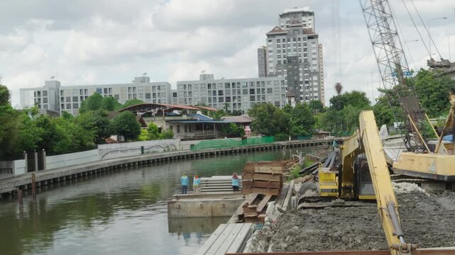 Construction crane over river against Bangkok skyline