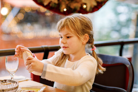 Little girl eating spaghetti in a restaurant. Happy child enjoying meal, family dining experience, real life moment of childhood joy and healthy eating indoors.