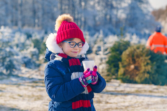 Little cute preschool girl drinking hot children punch or chocolate on German Christmas market. Happy child on traditional family market in Germany, Laughing boy in colorful winter clothes