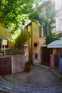 Charming narrow street in Gordes, Provence, France with stone houses, ivy covered walls and warm sunlight, picturesque village scene.