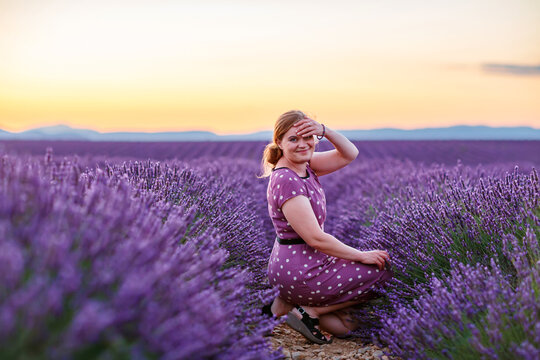 Woman farmer harvesting lavender in Provence field during golden hour, rural agriculture and blooming purple flowers landscape.