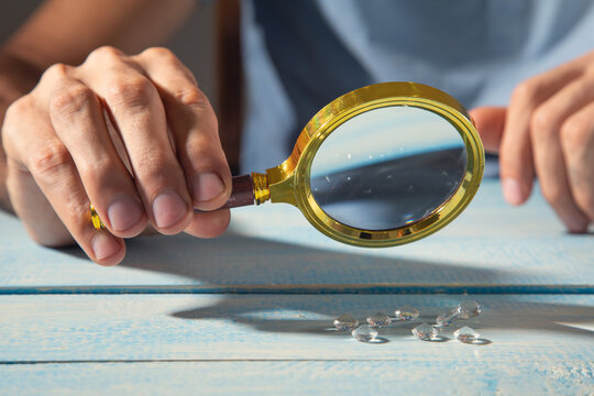 Man examines diamond through a magnifying glass.