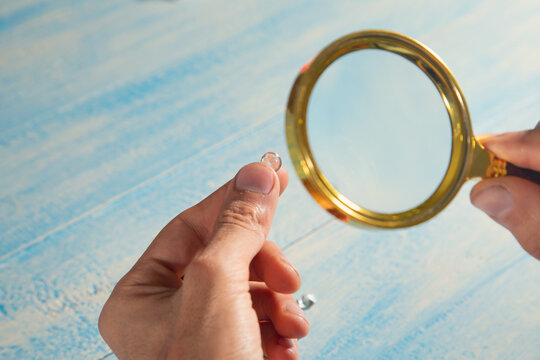 Man examines diamond through a magnifying glass.