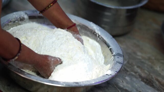 Hands mixing wheat flour for traditional Chhath Puja sweet preparation, a close up view of handmade festival food and Indian household cooking.