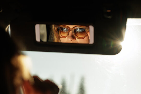 Woman Driver Wearing Sunglasses Faces Bright Sun Glare on Road