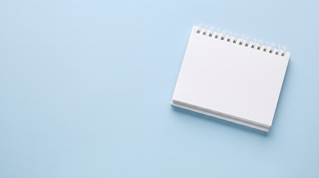 Blank spiral notebook on light blue background with copy spa.