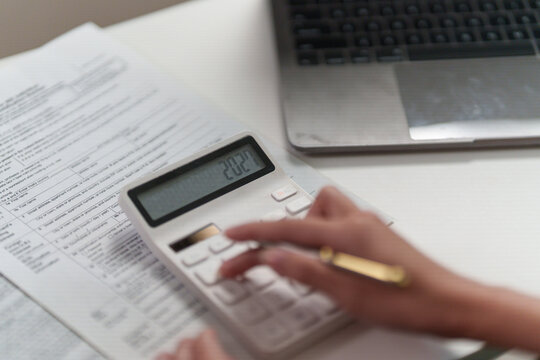Cropped hand using calculator over tax documents for financial planning