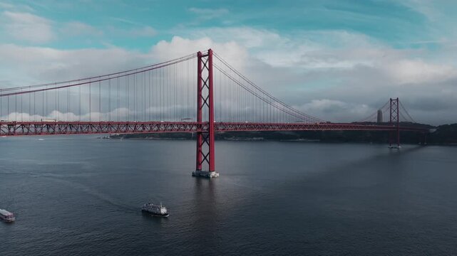 Aerial footage frames the red bridge towers, suspension cables and Lisbon waterfront from across the Tagus.