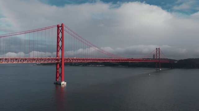 A red suspension bridge and small sailboats cross the Tagus River in this aerial view of Lisbon.
