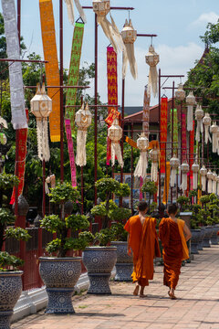 Monk walking under colorful lanterns in temple courtyard