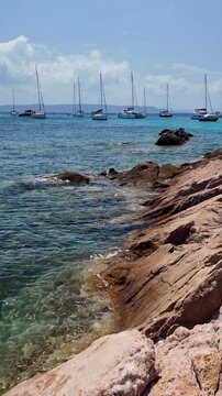 Panoramic vertical view of the turquoise bay with a rocky coastline with yachts and boats off the coast of Spargi Island in the La Maddalena archipelago, Sardinia, Italy
