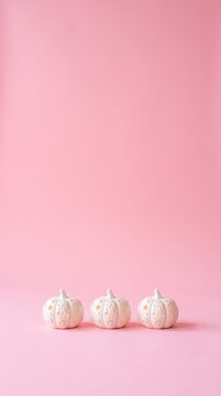 three small white decorative pumpkins with gold stars on a pink background for autumn and halloween decor