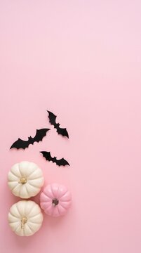 minimalist halloween decoration with white and pink pumpkins and black paper bats on pink background