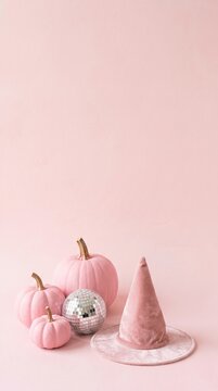 pink pumpkins and disco ball with velvet witch hat on pastel pink background for halloween decoration