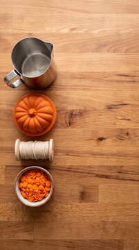fall halloween themed items including pumpkin candle holder orange confetti and twine on wooden table