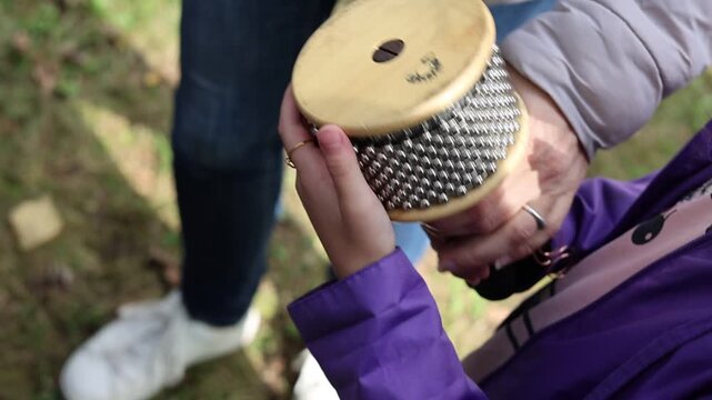 Close-up of passing a cabasa percussion instrument between people outdoors for music concepts