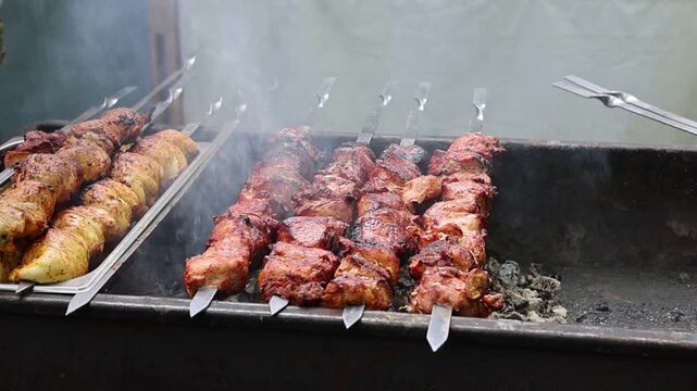 Juicy marinated meat and potatoes grilling on metal skewers over hot charcoal coals in a brazier