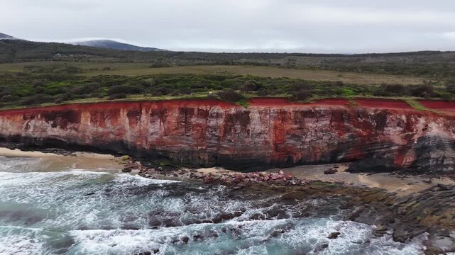 Aerial video flying over the rugged coastline at Lake Arragan, featuring sandy shoreline, rocky formations and waves rolling in from the Pacific Ocean