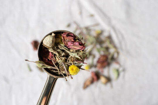Close up of a spoonful of herbal tea on a natural linen tablecloth, rustic ingredient still life and organic wellness concept