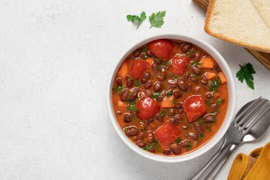 Homemade bean stew with tomatoes served in a bowl on a light background, hearty seasonal comfort food and healthy vegetarian meal