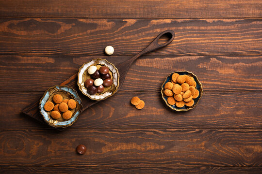 Assorted Dutch kruidnoten cookies arranged in decorative bowls on a rustic wooden surface, traditional treats for Sinterklaas Saint Nicholas day celebrations, view from above with copy space