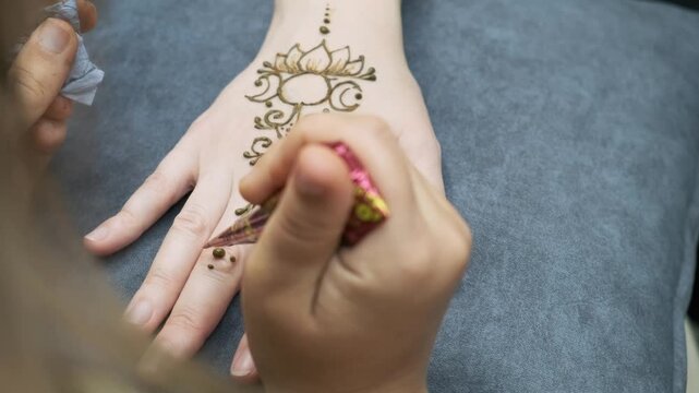 artist applying mehndi design on female hand with henna cone. traditional mehndi art creates beautiful temporary body tattoo. mehndi ceremony is popular cultural tradition for wedding