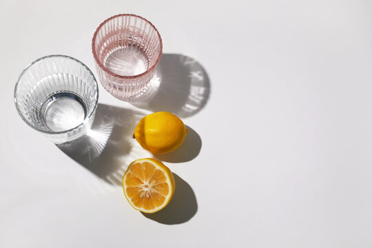 Lemons and glasses creating aesthetic shadows on white background