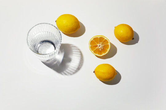 Fresh lemons and water glass casting shadows