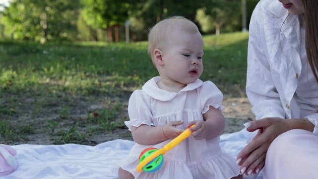 Baby playing with rattle on a picnic blanket in the park