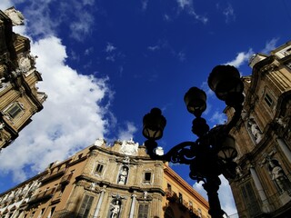 Ornate wrought-iron street lamp frames the baroque facades of the Quattro Canti against a deep blue sky in Palermo, Italy, January 12, 2023. © Isabella
