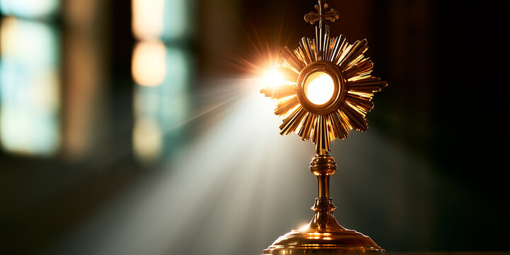 Corpus christi golden monstrance eucharist display for adoration in church with light shining from window view 
