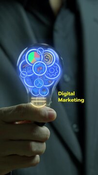 Businessman hand holding incandescent lightbulb vertical shot with gear mechanism and digital marketing text. Creative online advertising innovation, promotional strategy, and campaign idea concept.