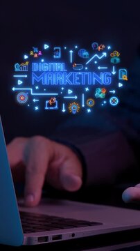 Businessman typing on laptop keyboard vertical shot with glowing digital marketing service cloud icons. Online advertising campaign operations, corporate media strategy, and promotion idea concept.