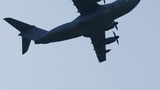 Impressive military transport plane, an Airbus A400M Atlas, performing a flight demonstration during an airshow with a fighter escort