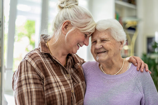 Happy senior woman and her adult daughter at home
