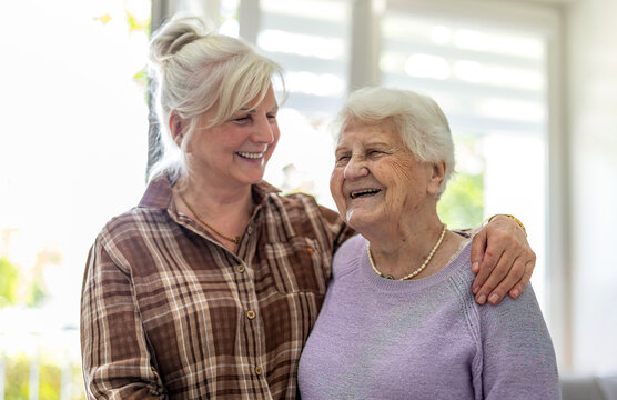 Happy senior woman and her adult daughter at home
