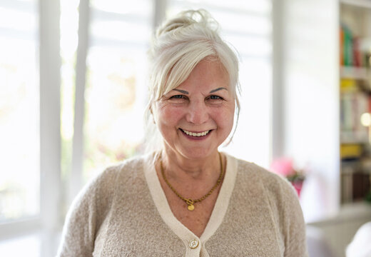 Senior woman smiling at camera in living room at home
