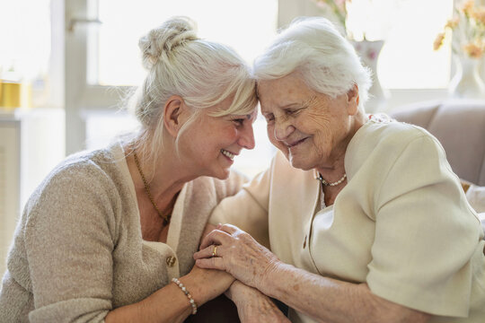 Happy senior woman and her adult daughter at home
