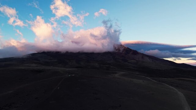 Dramatic pink clouds swirling around the peak of the chimborazo volcano in ecuador at sunset