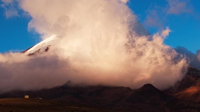 Dramatic clouds rolling over the peak of the chimborazo volcano in the andes of ecuador at sunset