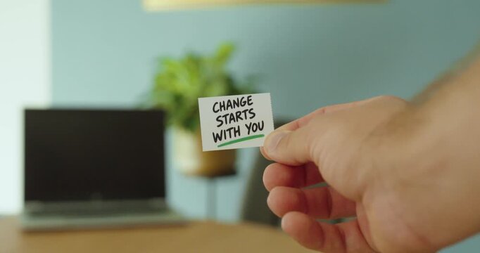 Close-up of hand holding a Change Starts With You message card, representing personal responsibility, positive change, motivation and individual action.