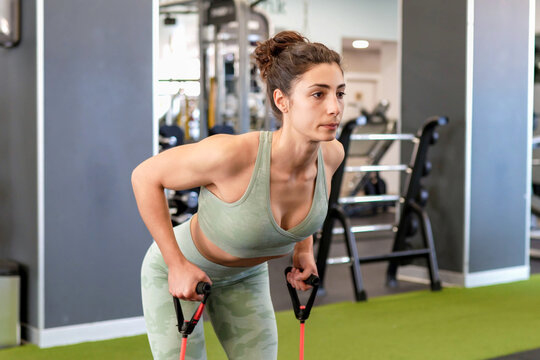 Woman concentrates fully on resistance band rowing exercise guided professionally