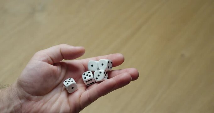 Close-up of a hand holding multiple white dice, representing luck, chance, probability and gaming.