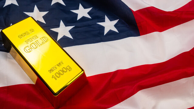 Gold bar lies on top of a rippled United States of American flag.
Gold serves as a primary safe-haven asset for investors during economic uncertainty.